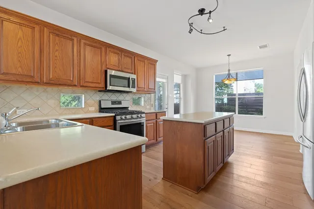 a kitchen with stainless steel appliances wooden cabinets a stove top oven a sink and dishwasher