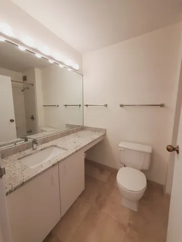 a bathroom with a granite countertop sink a toilet and a mirror