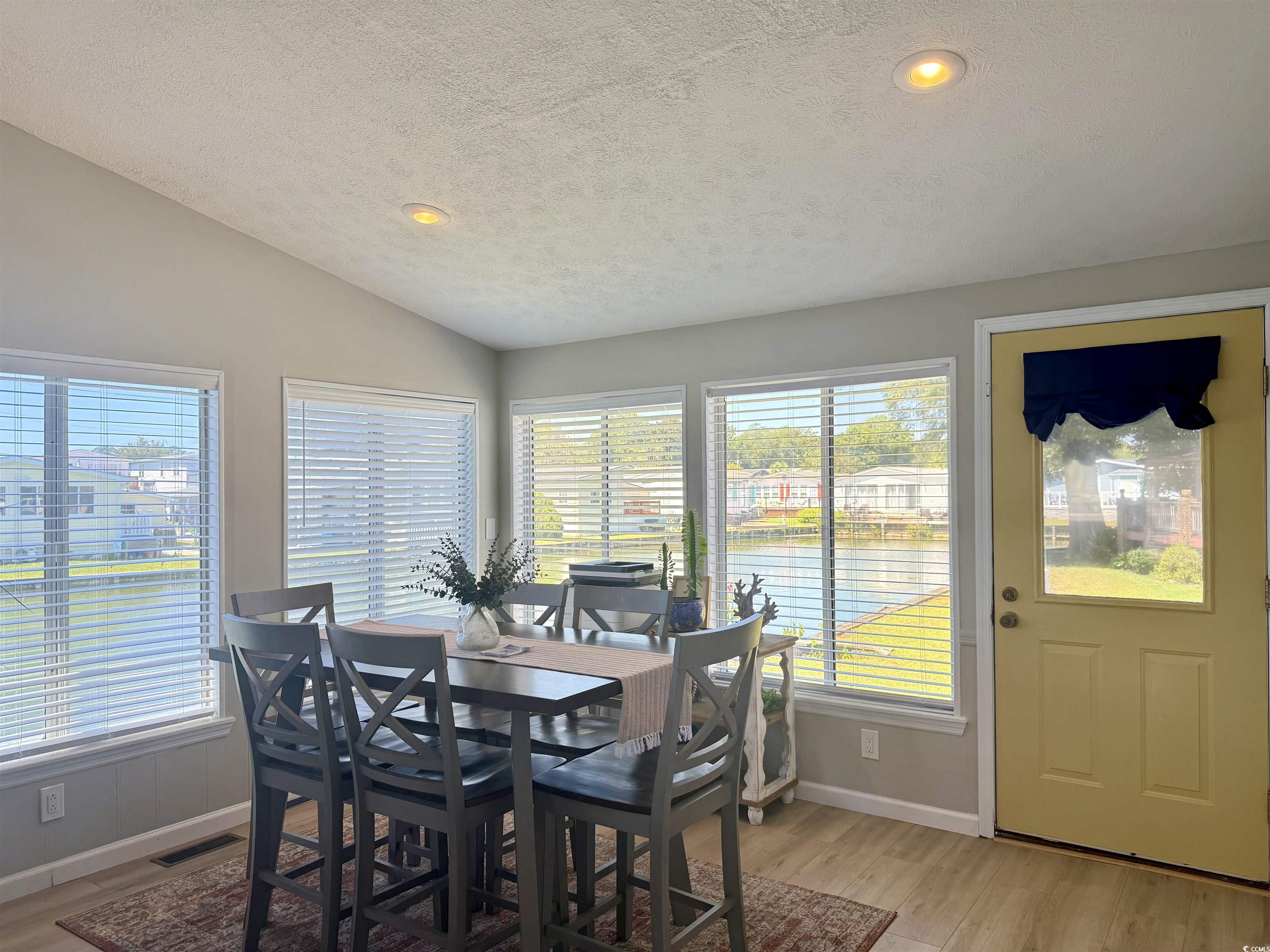 405 Twin Lakes Surfside Beach, SC 29575 - Photo 11 of 36 Dining area with a water view, light wood-style floors, healthy amount of natural light, a textured ceiling, and vaulted ceiling