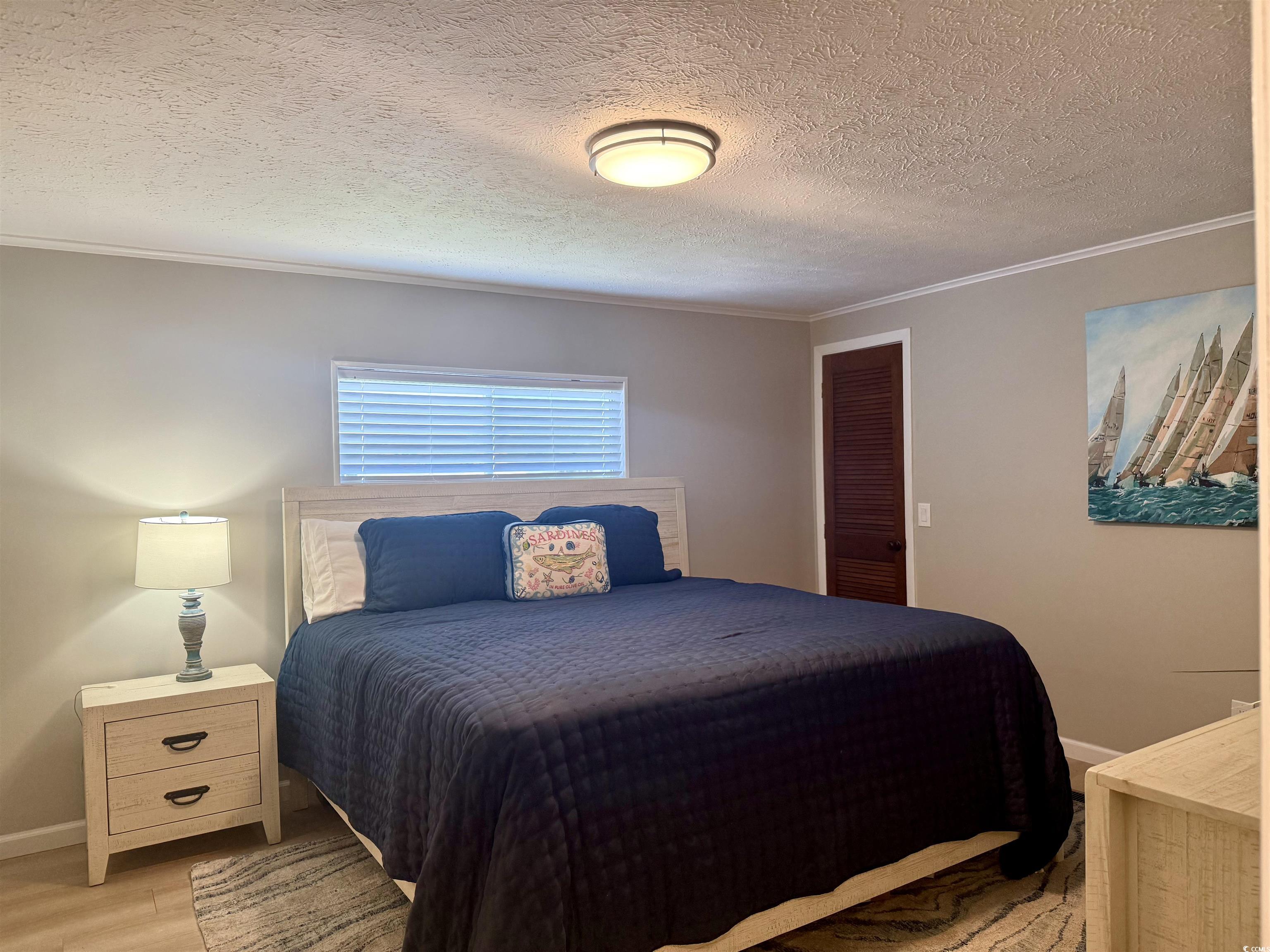 405 Twin Lakes Surfside Beach, SC 29575 - Photo 14 of 36 Bedroom with crown molding, light wood finished floors, a textured ceiling, and a closet