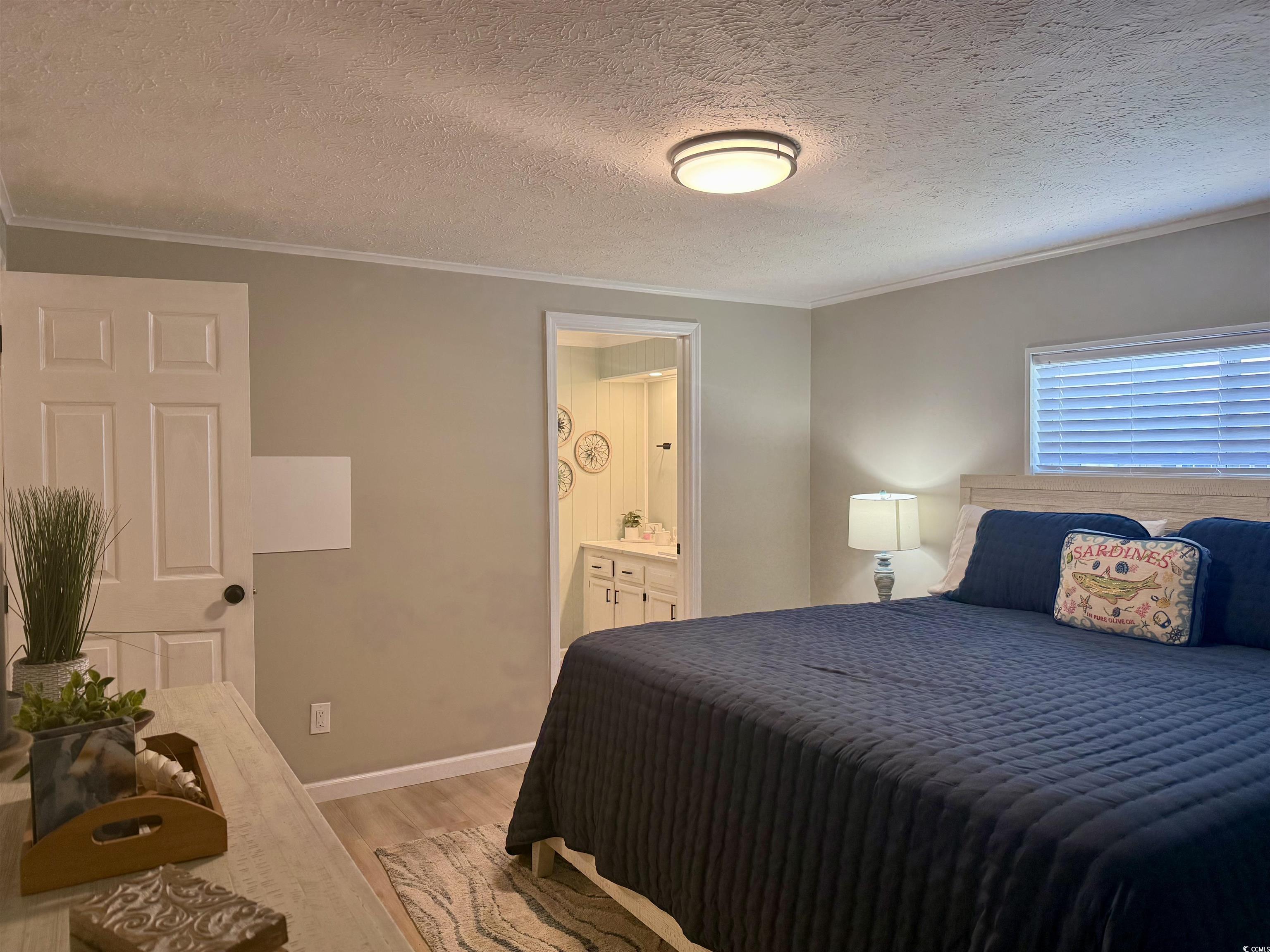405 Twin Lakes Surfside Beach, SC 29575 - Photo 16 of 36 Bedroom with ornamental molding, light wood-style floors, a textured ceiling, and ensuite bath