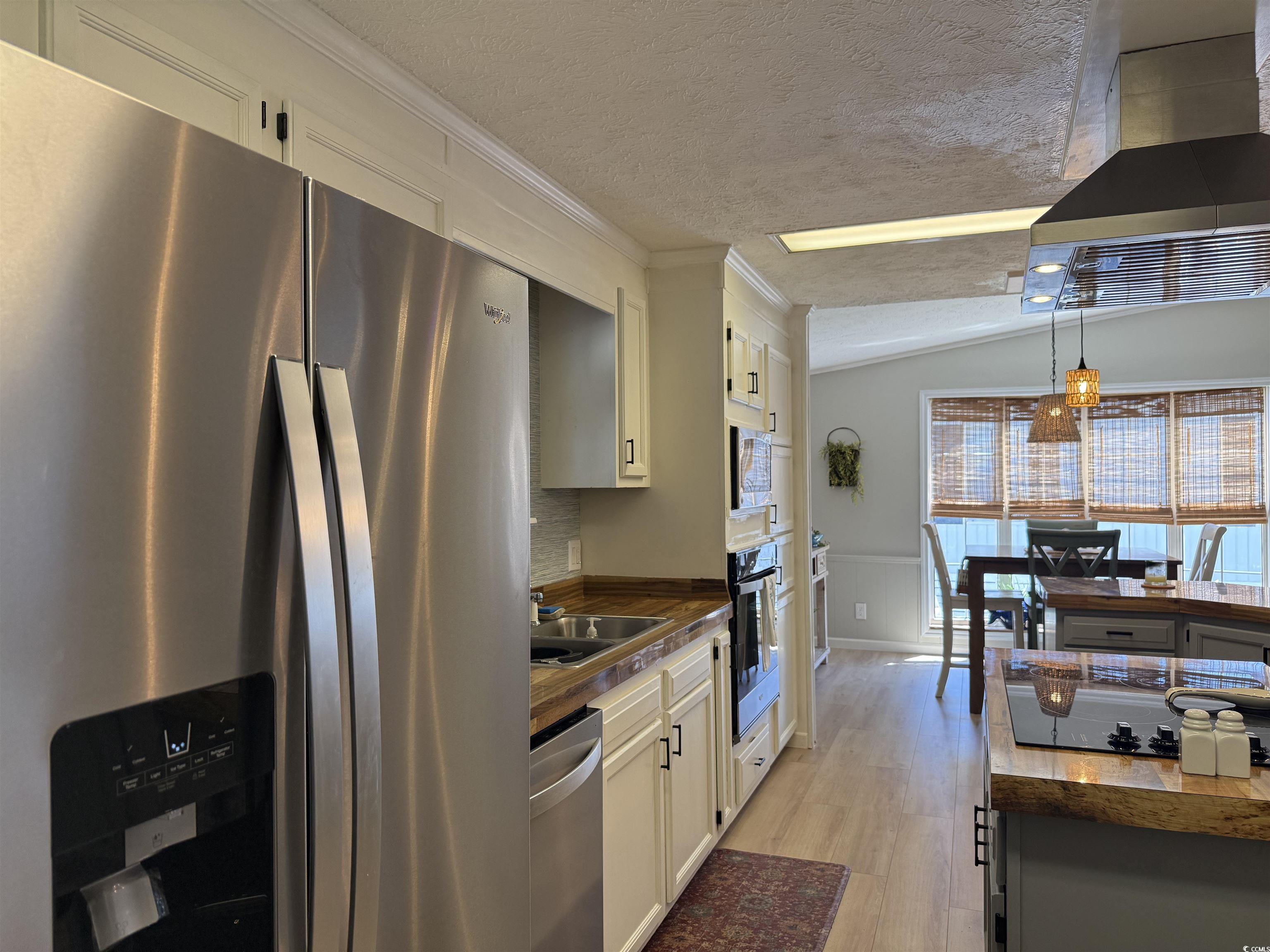 405 Twin Lakes Surfside Beach, SC 29575 - Photo 2 of 36 Kitchen featuring black appliances, a textured ceiling, light wood finished floors, wall chimney range hood, and white cabinetry