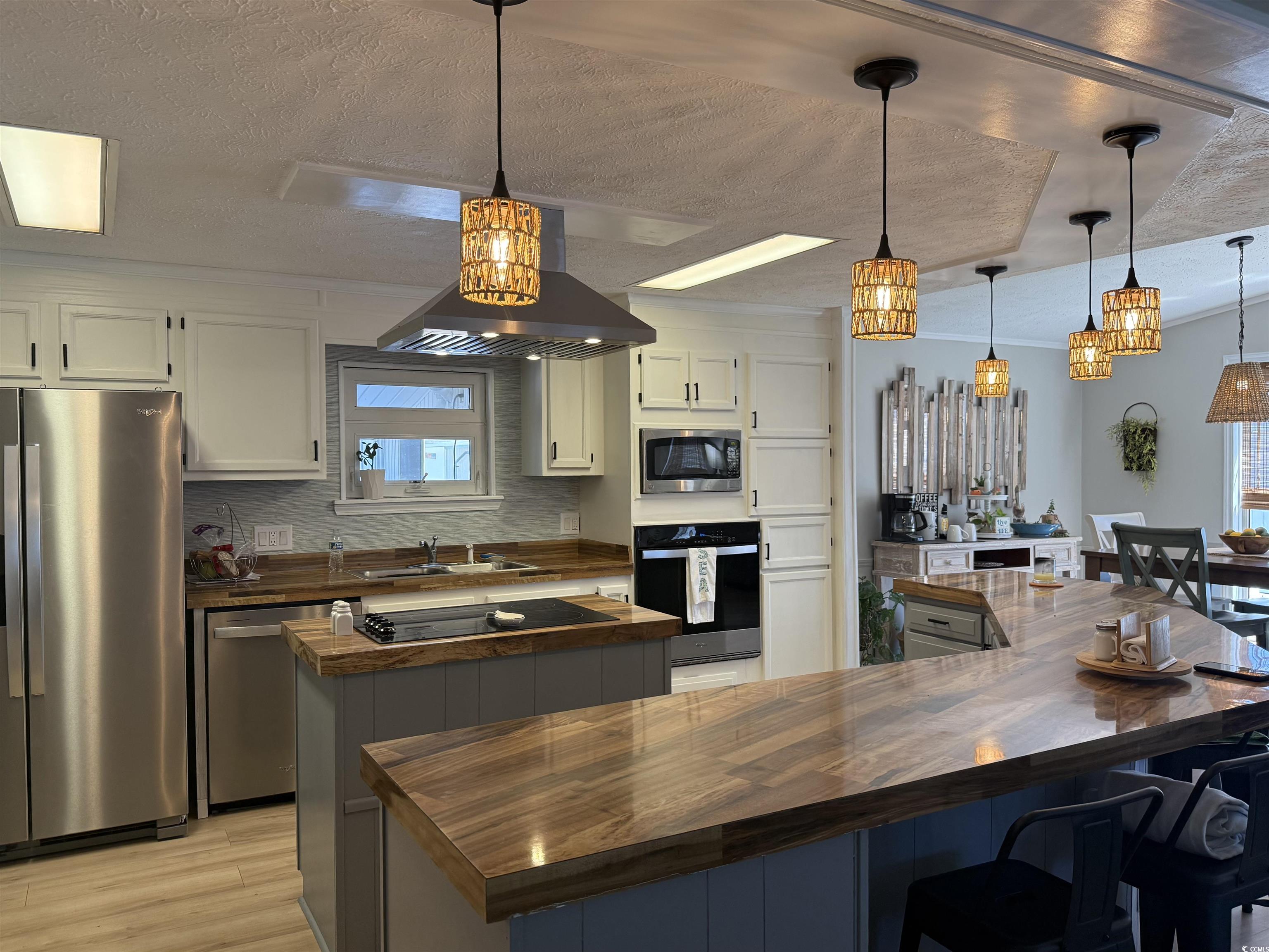 405 Twin Lakes Surfside Beach, SC 29575 - Photo 4 of 36 Kitchen featuring a kitchen island, a textured ceiling, black appliances, pendant lighting, and a breakfast bar area