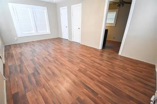 an empty room with wooden floor and windows