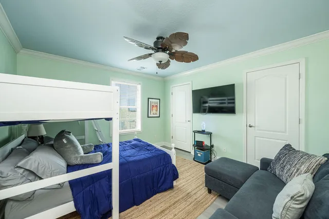 a living room with furniture a flat screen tv and a ceiling fan