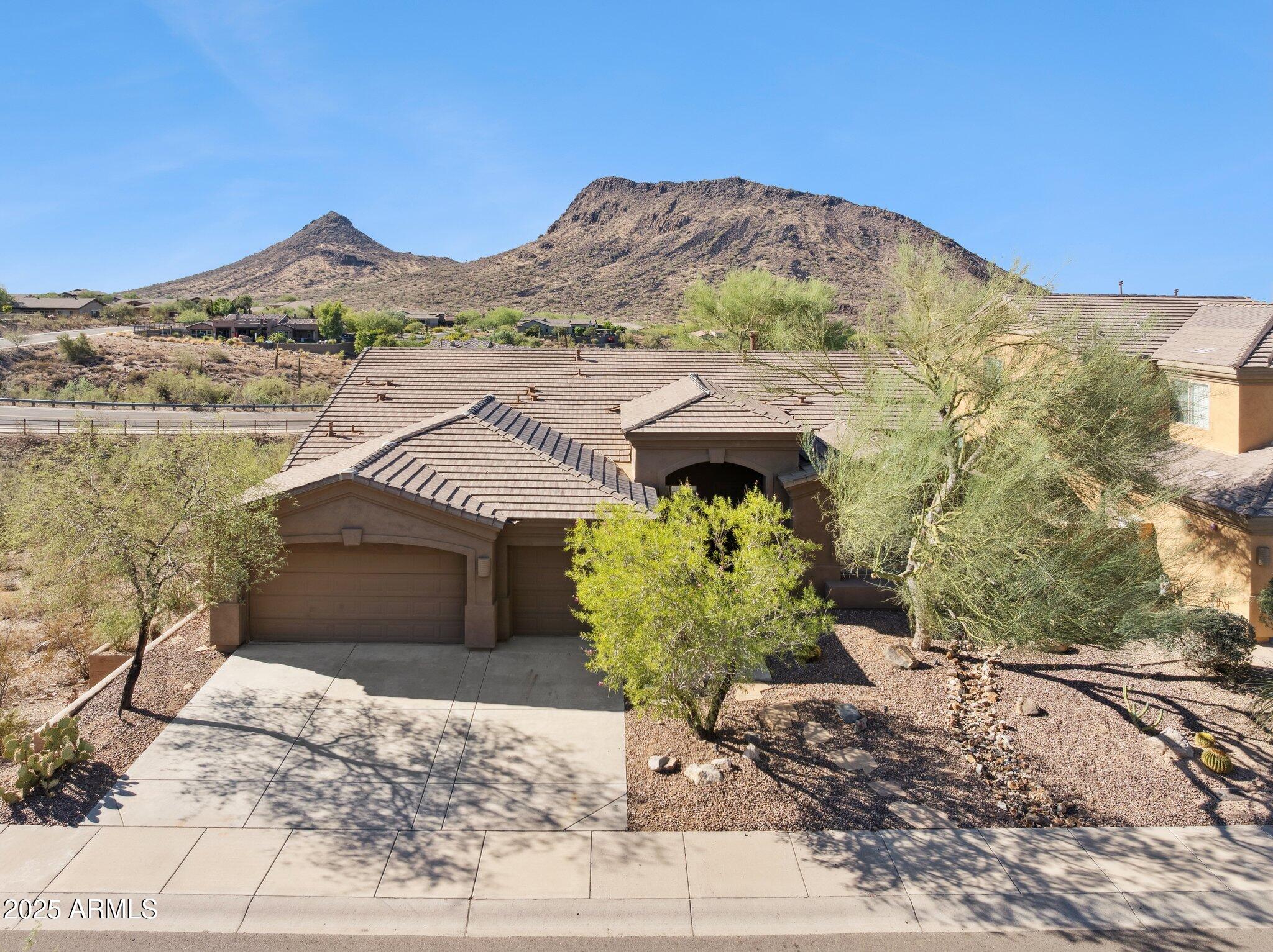 a front view of a house with a yard and mountain view in back