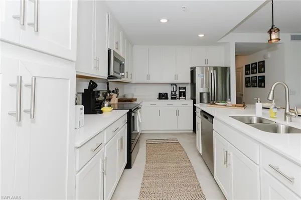a kitchen with white cabinets sink and stainless steel appliances