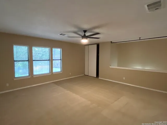 an empty room with a window and a ceiling fan