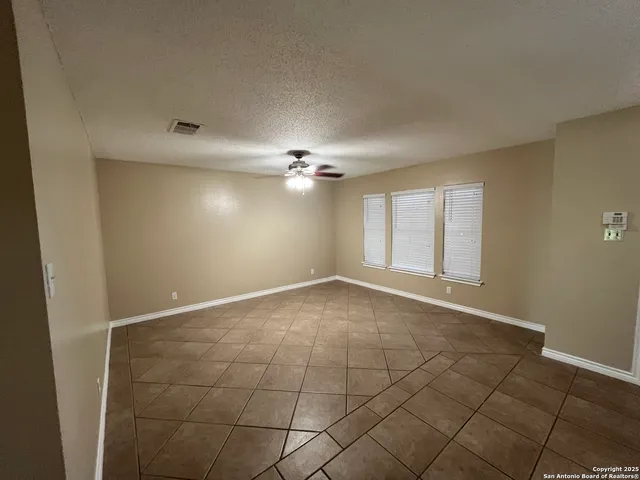 a view of an empty room with a chandelier fan