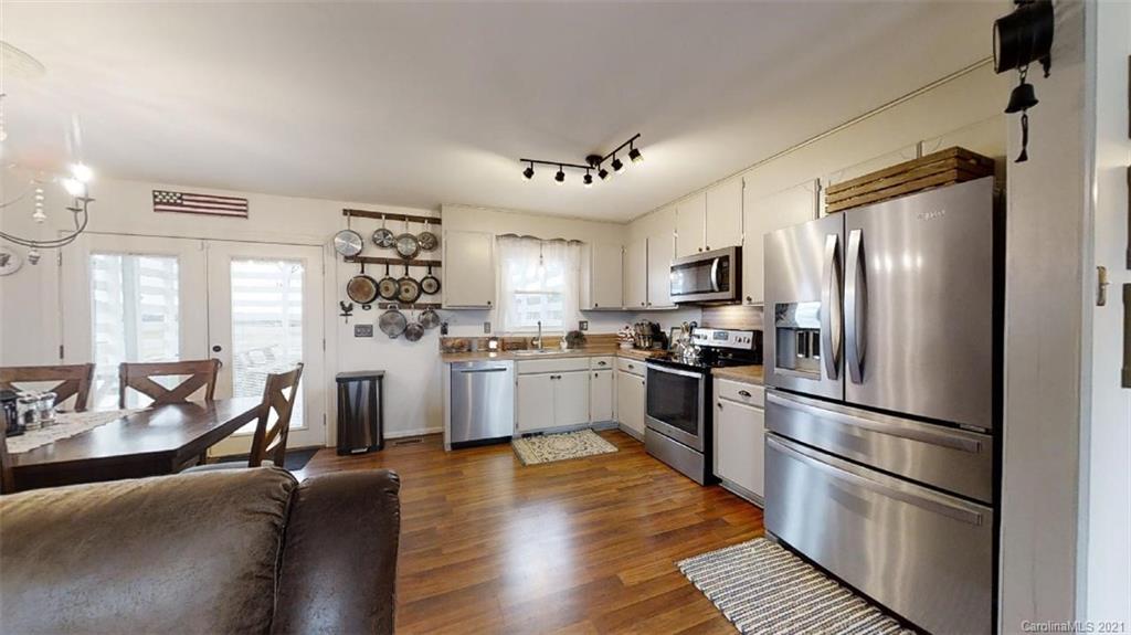 228 Huffstetler Lake Road Dallas, NC 28034 - Photo 14 of 27 a kitchen with stainless steel appliances granite countertop a refrigerator a stove a sink dishwasher a dining table and chairs with wooden floor