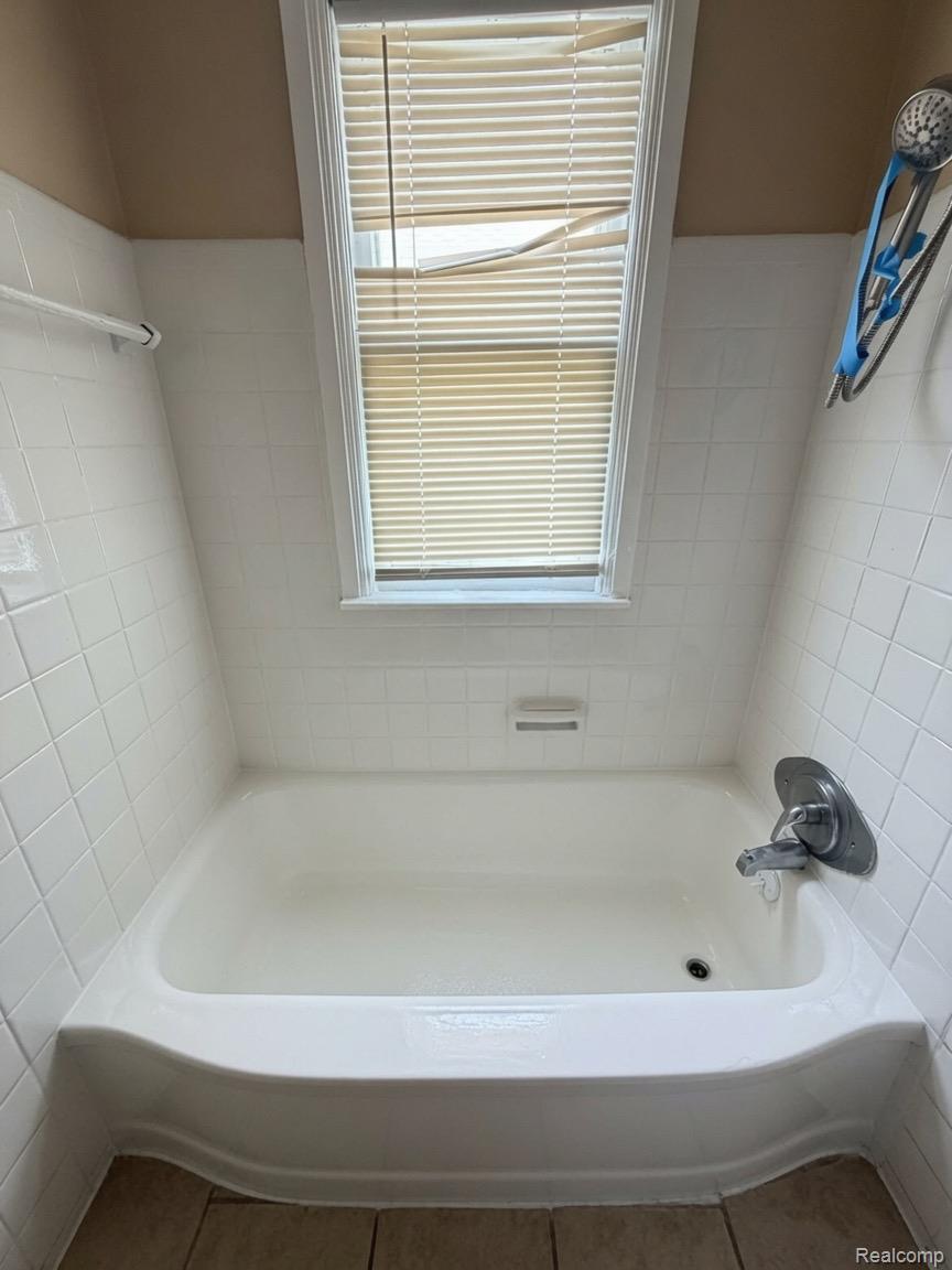 7286 Faust Avenue Detroit, MI 48228 - Photo 19 of 19 White tiled bathtub with an overhead window, polished chrome faucet, and tiled flooring