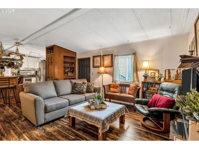 a kitchen with stainless steel appliances a refrigerator a sink dishwasher a dining table and chairs with wooden floor