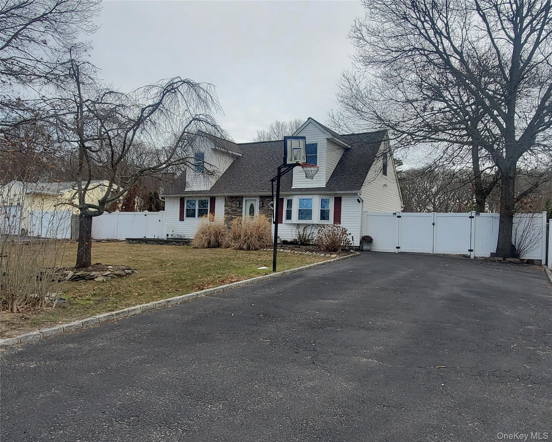 Cape cod house featuring a gate, asphalt driveway, and roof with shingles