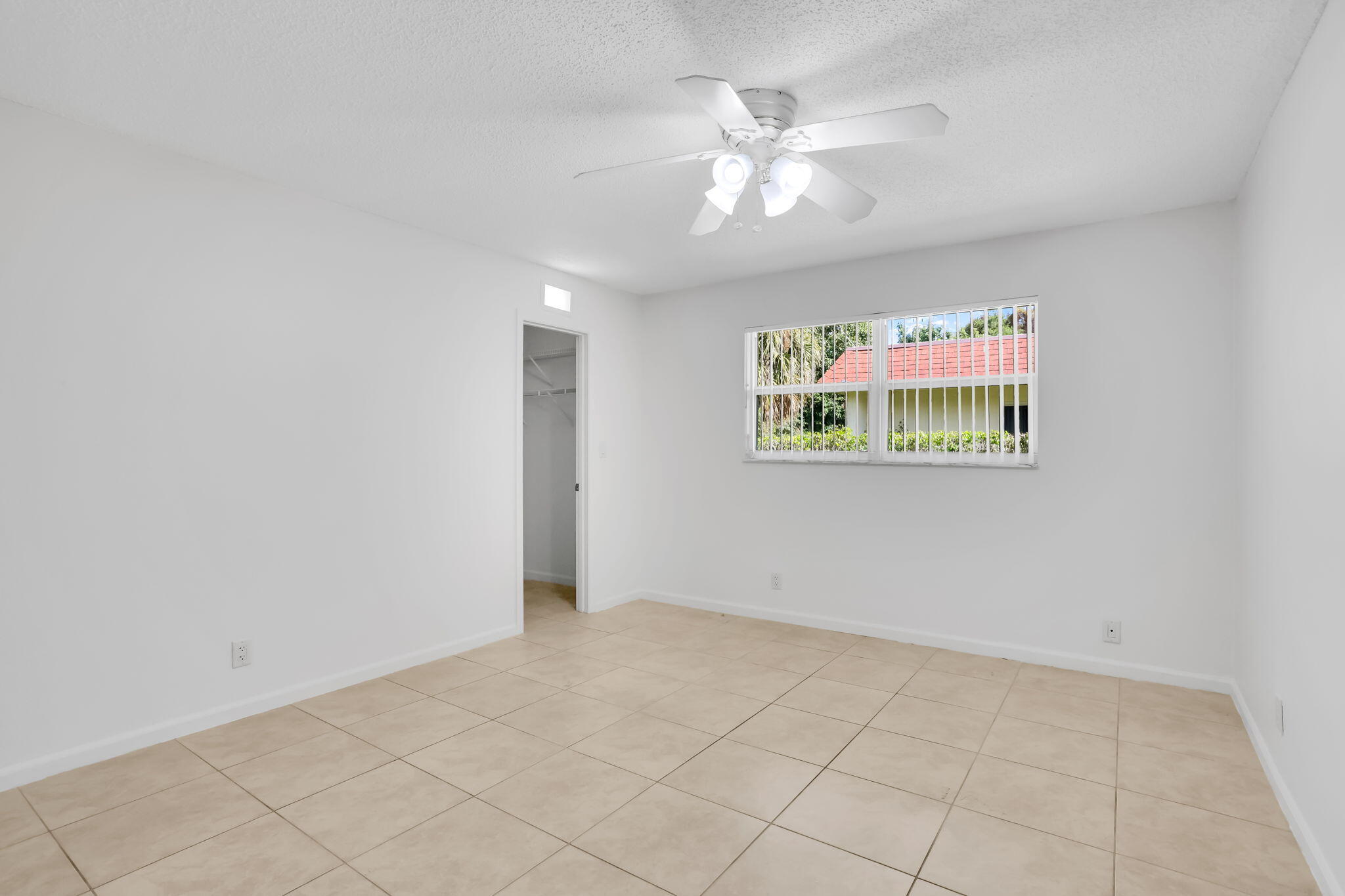 89 Lariat Circle Boca Raton, FL 33487 - Photo 16 of 31 an empty room with a chandelier fan and windows