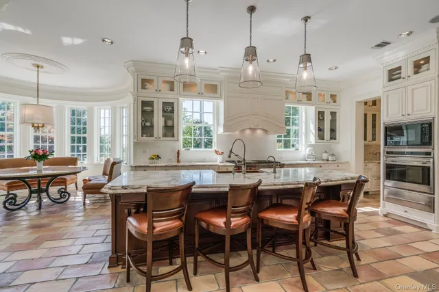 an open kitchen with granite countertop a stove a sink a dining table and chairs