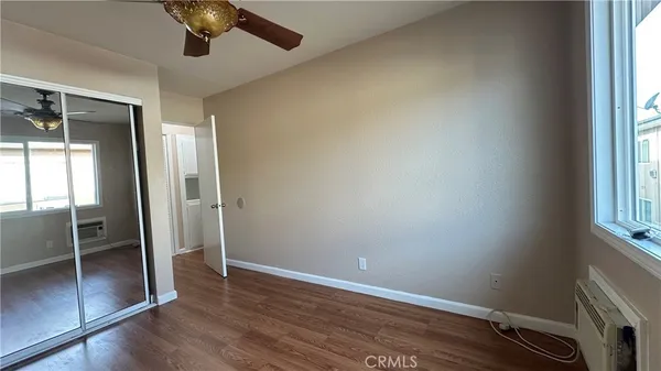 an empty room with wooden floor fan and windows
