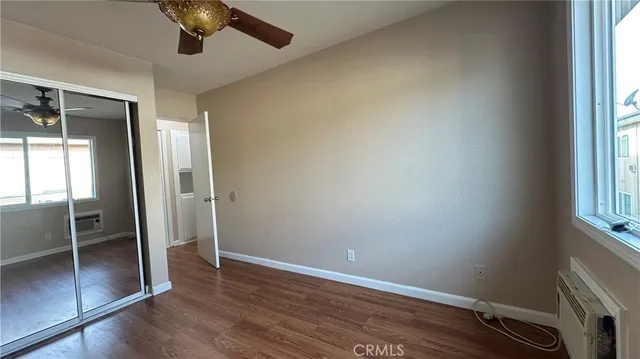 an empty room with wooden floor fan and windows