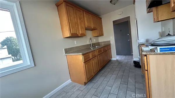 a kitchen with granite countertop wooden cabinets a sink a window and stainless steel appliances