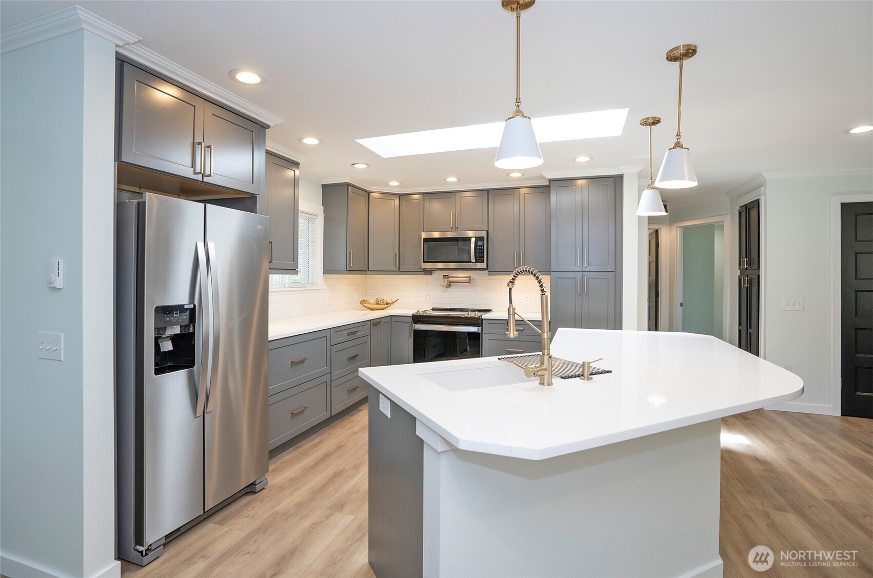 15512 Elm Street East Sumner, WA 98390 - Photo 11 of 37 a kitchen with a white center island a refrigerator cabinets and wooden floor
