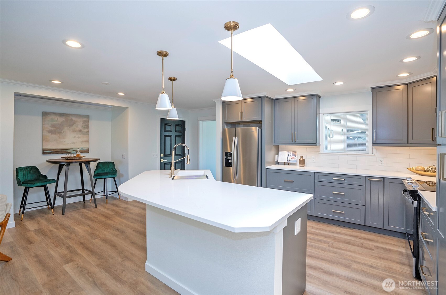 15512 Elm Street East Sumner, WA 98390 - Photo 12 of 37 a large kitchen with kitchen island a island a stove a sink a dining table and chairs with wooden floor