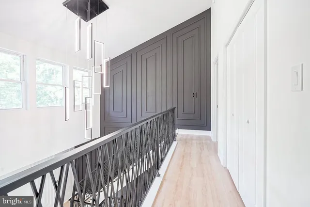 a view of a hallway with wooden floor and chandelier