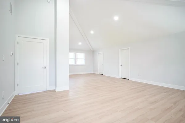 a view of an empty room with wooden floor and windows