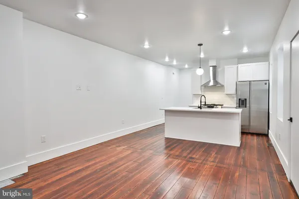 a view of kitchen with kitchen island wooden floors and stainless steel appliances