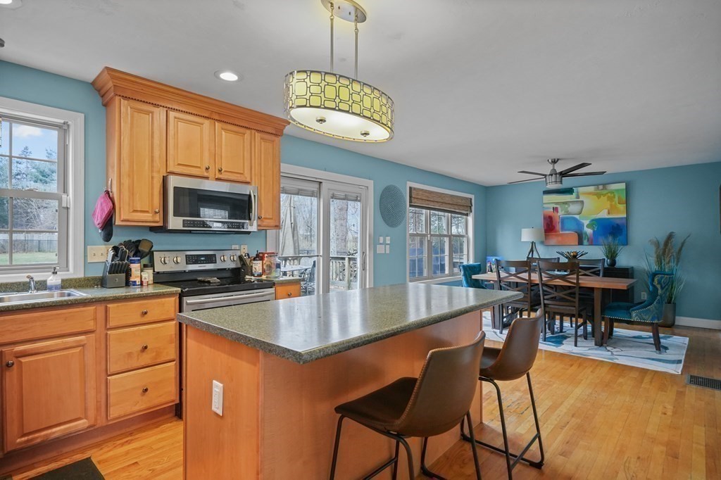 3 Carter Way Worcester, MA 01609 - Photo 11 of 32 a kitchen with stainless steel appliances granite countertop a stove top oven a sink a dining table and chairs with wooden floor