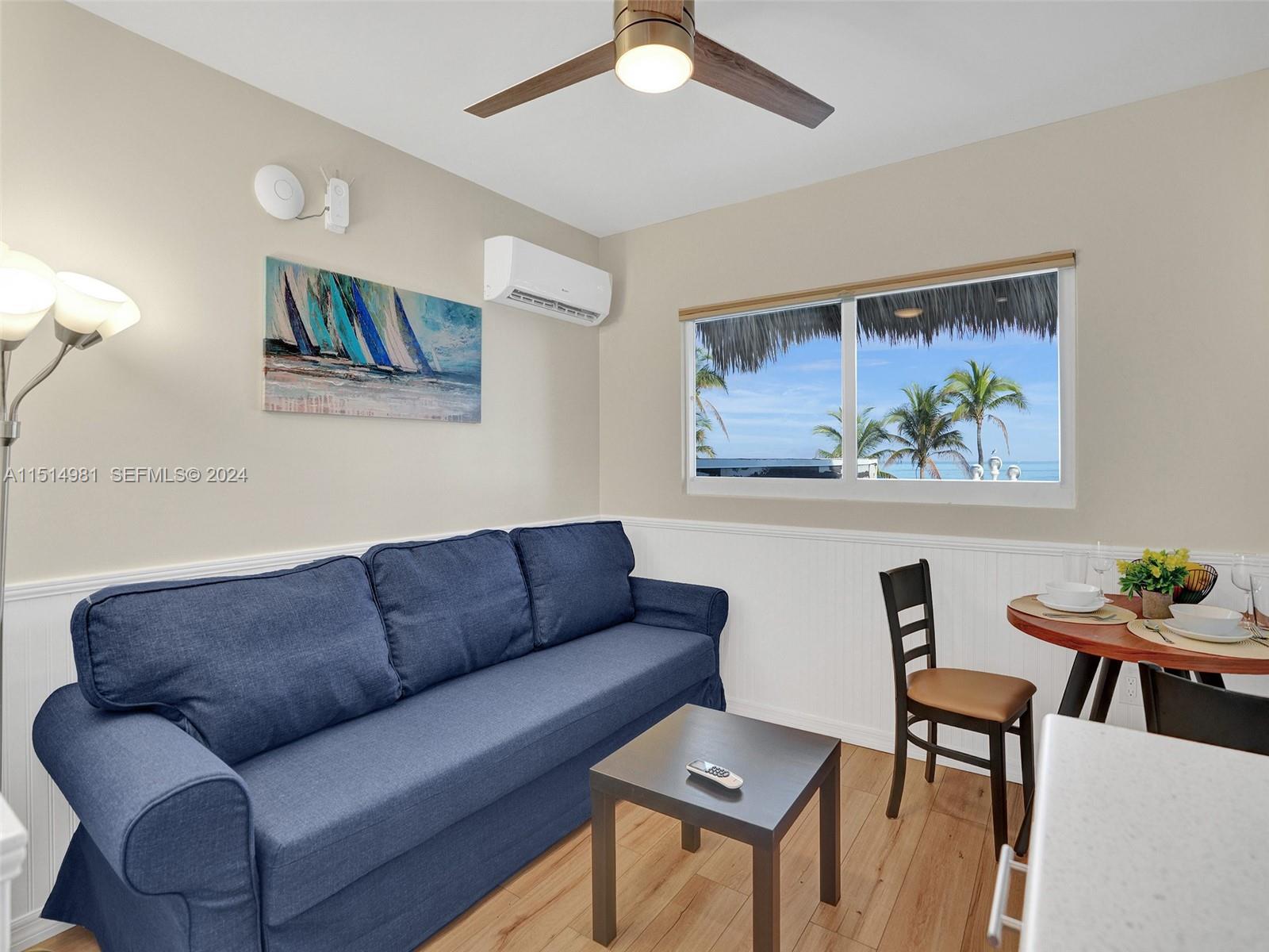 900 North Surf Road, Unit 2 Hollywood, FL 33019 - Photo 40 of 48 a blue couch sitting in a living room with furniture and a painting on the wall