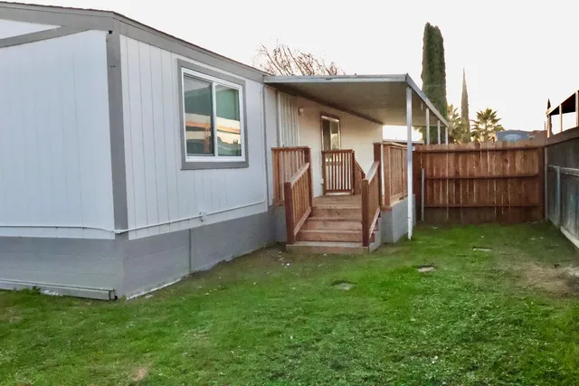 a view of a backyard with wooden fence and large trees