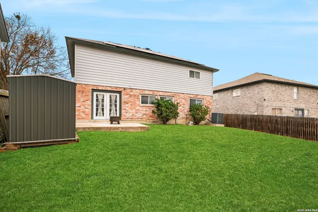 a view of a backyard with potted plants and large tree