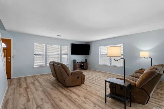 a living room with furniture a flat screen tv and a wooden floor
