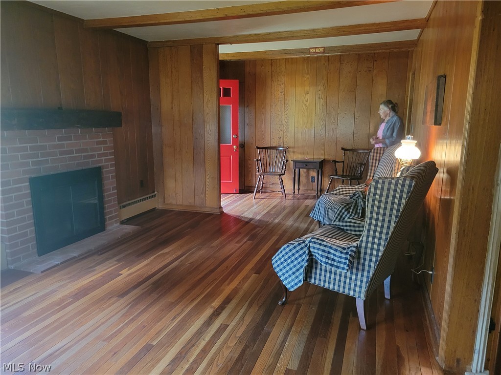 7357 Westview Road Kent, OH 44240 - Photo 8 of 30 Living area with beamed ceiling, wooden walls, a fireplace, baseboard heating, and hardwood / wood-style flooring