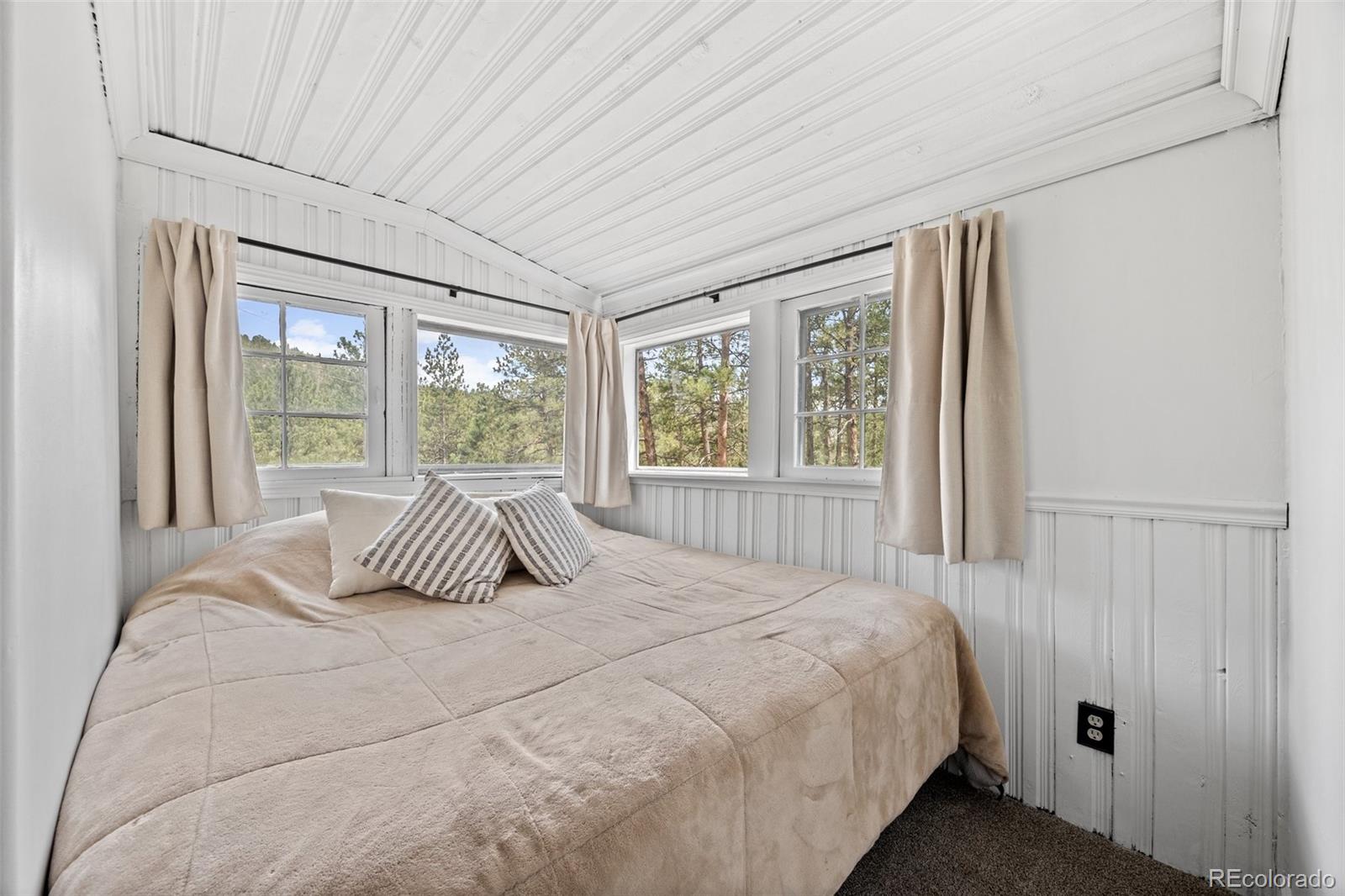 15535 South Elk Creek Road Pine, CO 80470 - Photo 17 of 25 a bedroom with a large bed and a large window