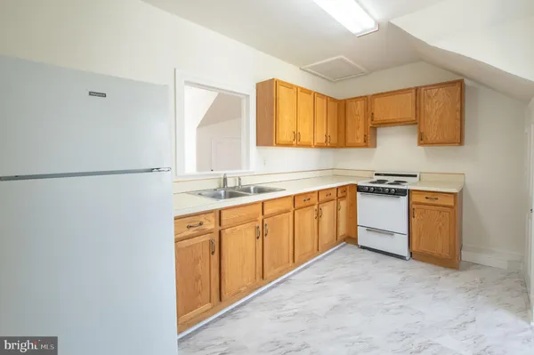 a kitchen with granite countertop a refrigerator a sink a stove and white cabinets