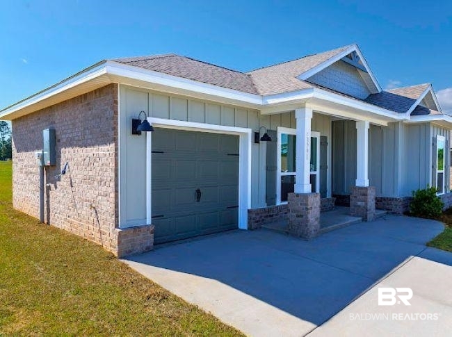 13791 Logan Place Foley, AL 36535 - Photo 2 of 25 Modern ranch-style home featuring a two-car garage, partial brick facade, light gray siding, a covered front porch, and a gray shingle roof