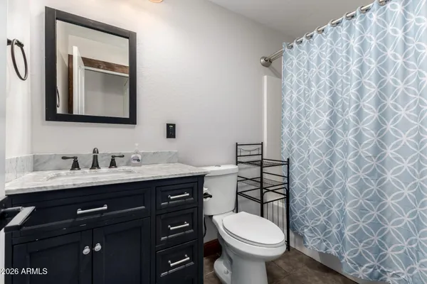 a bathroom with a granite countertop toilet sink and mirror