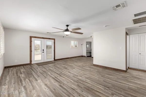 a view of an empty room with wooden floor and a ceiling fan