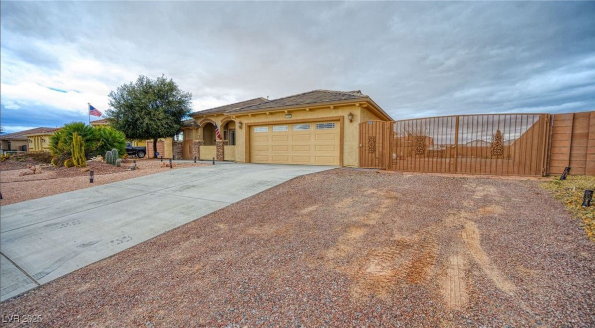 View of front of property with a gate, concrete driveway, stucco siding, and an attached garage