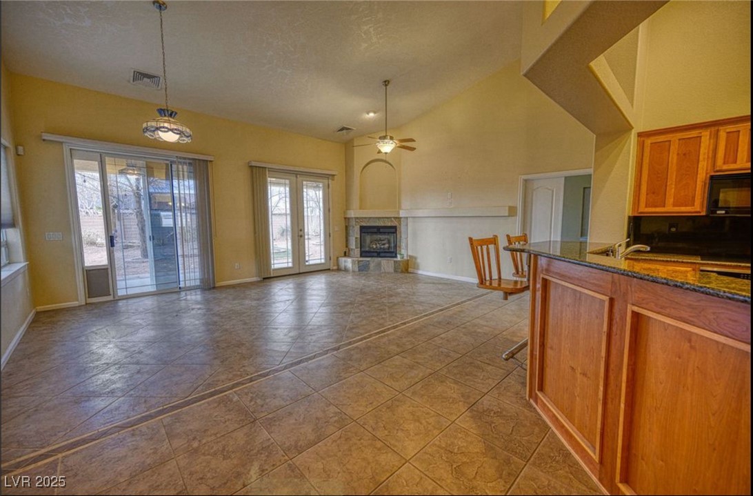 6780 Sandpebble Street Pahrump, NV 89061 - Photo 25 of 25 Kitchen with brown cabinetry, dark stone countertops, black microwave, a ceiling fan, and open floor plan