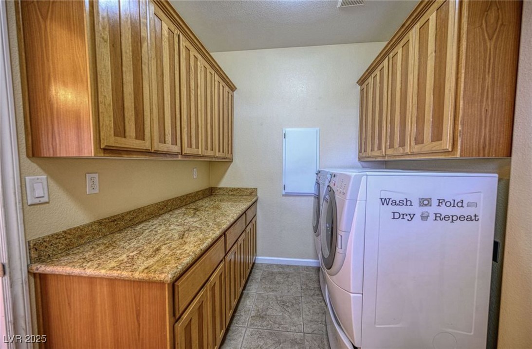 6780 Sandpebble Street Pahrump, NV 89061 - Photo 23 of 25 Washroom with cabinet space, light tile patterned floors, washer and clothes dryer, a textured ceiling, and a textured wall