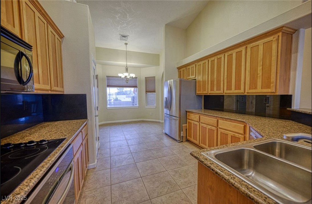 6780 Sandpebble Street Pahrump, NV 89061 - Photo 2 of 25 Kitchen featuring hanging light fixtures, black appliances, a chandelier, light stone counters, and light tile patterned flooring