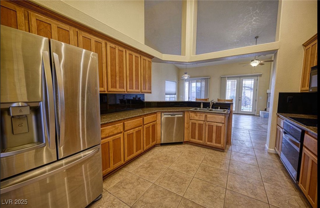 6780 Sandpebble Street Pahrump, NV 89061 - Photo 3 of 25 Kitchen featuring stainless steel appliances, brown cabinetry, pendant lighting, a peninsula, and light tile patterned floors