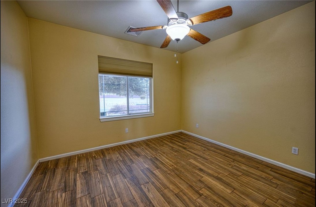6780 Sandpebble Street Pahrump, NV 89061 - Photo 8 of 25 Empty room with dark wood-style floors and a ceiling fan