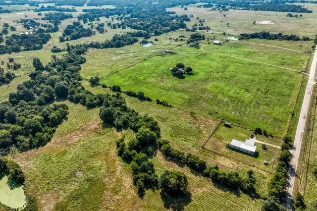 an aerial view of residential houses with outdoor space and trees
