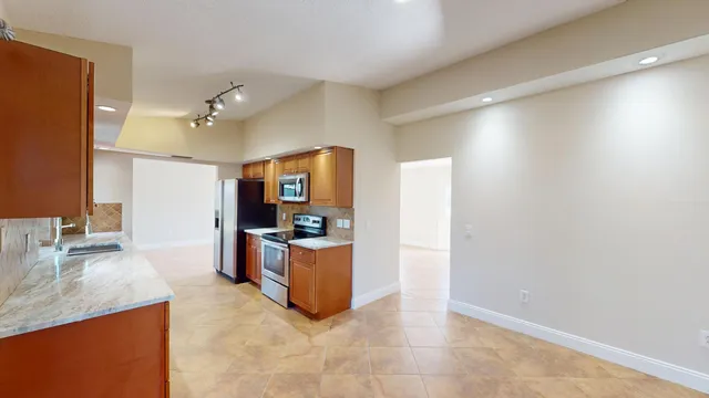 a room with stainless steel appliances kitchen island granite countertop a refrigerator and a sink