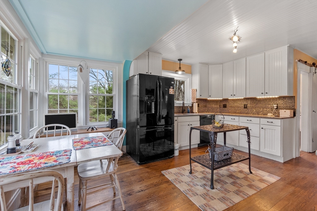 613 Petersham Road Athol, MA 01331 - Photo 20 of 41 a kitchen with a refrigerator a stove top oven and a dining table with wooden floor