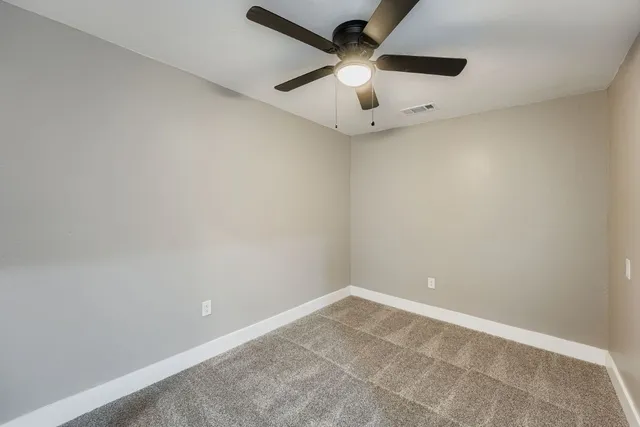 an empty room with a window and a fan