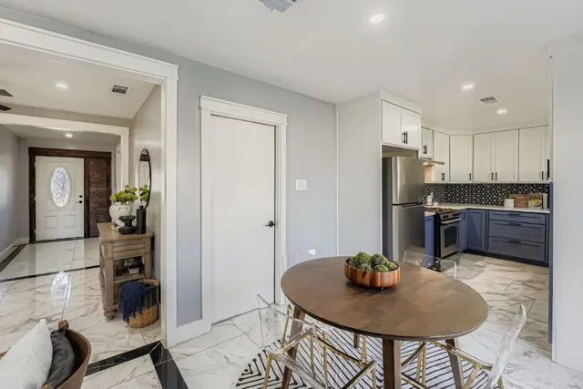 a kitchen with stainless steel appliances granite countertop a refrigerator a stove a sink a dining table and chairs