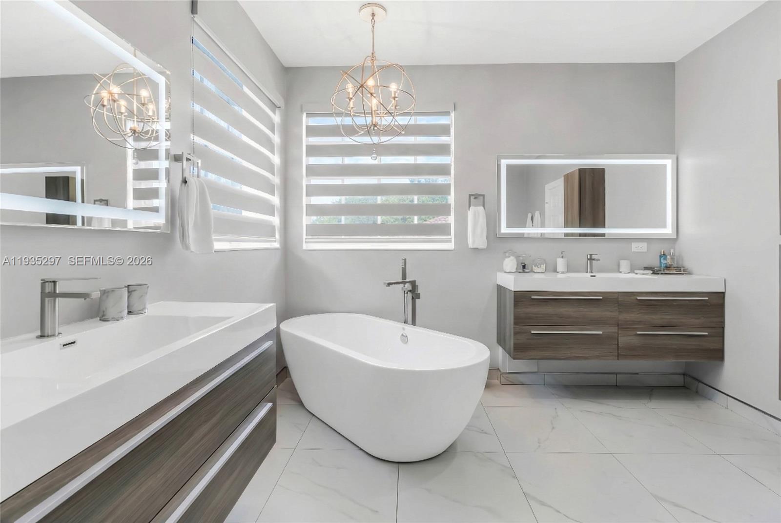 5311 Southwest 184th Way Miramar, FL 33029 - Photo 30 of 81 a bathroom with a white tub a double vanity sink a window and mirror